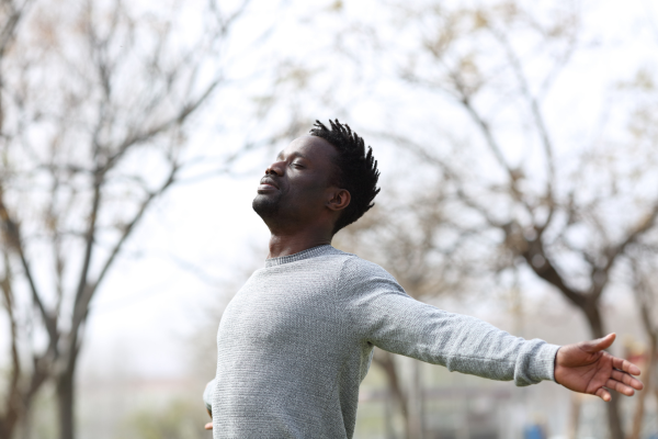 Man standing with eyes closed and arms spread