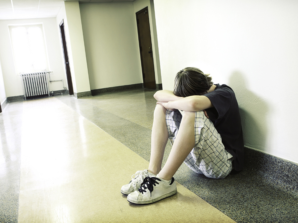 Teen sitting covering face