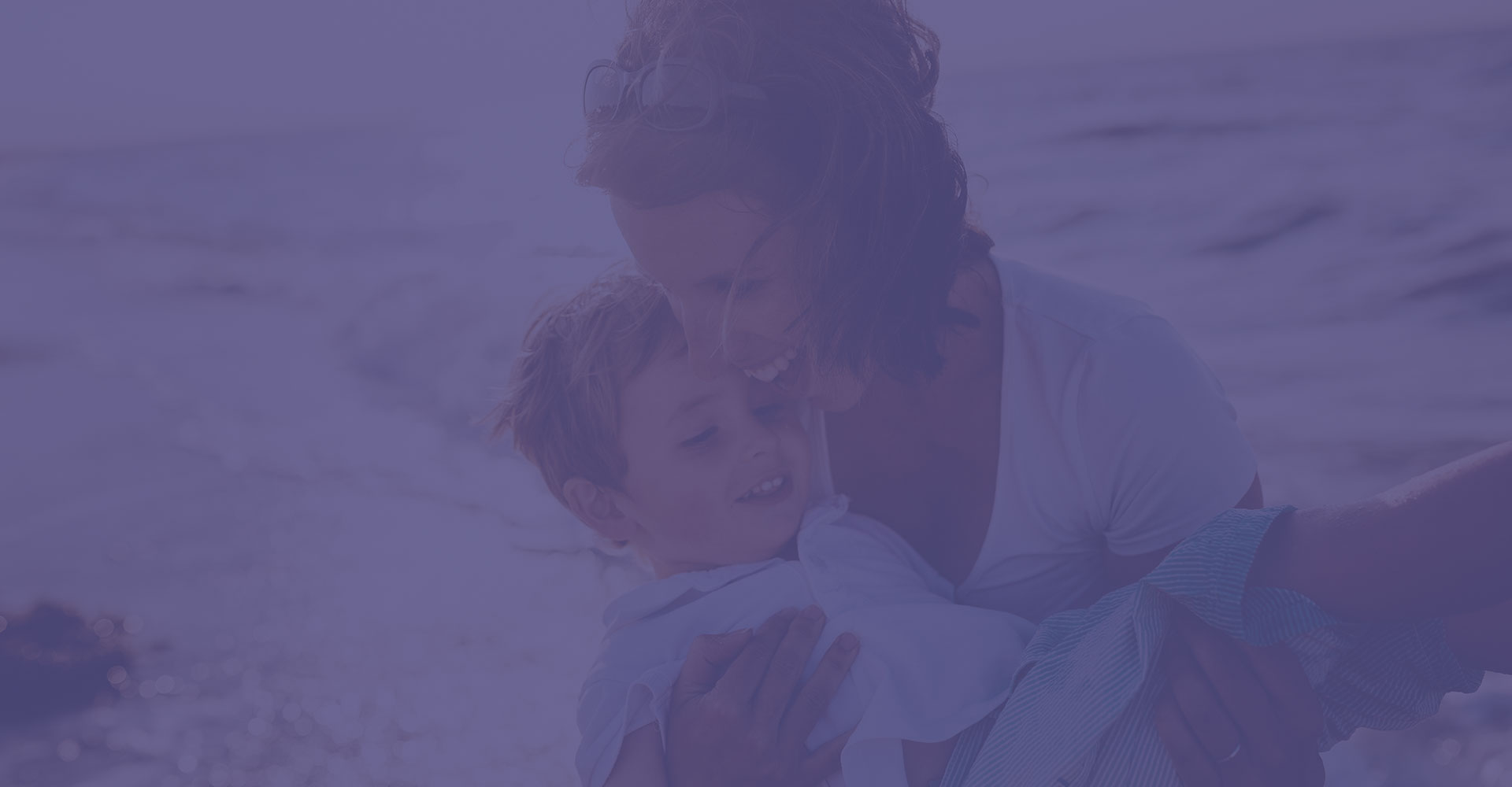 Woman holding child by the ocean