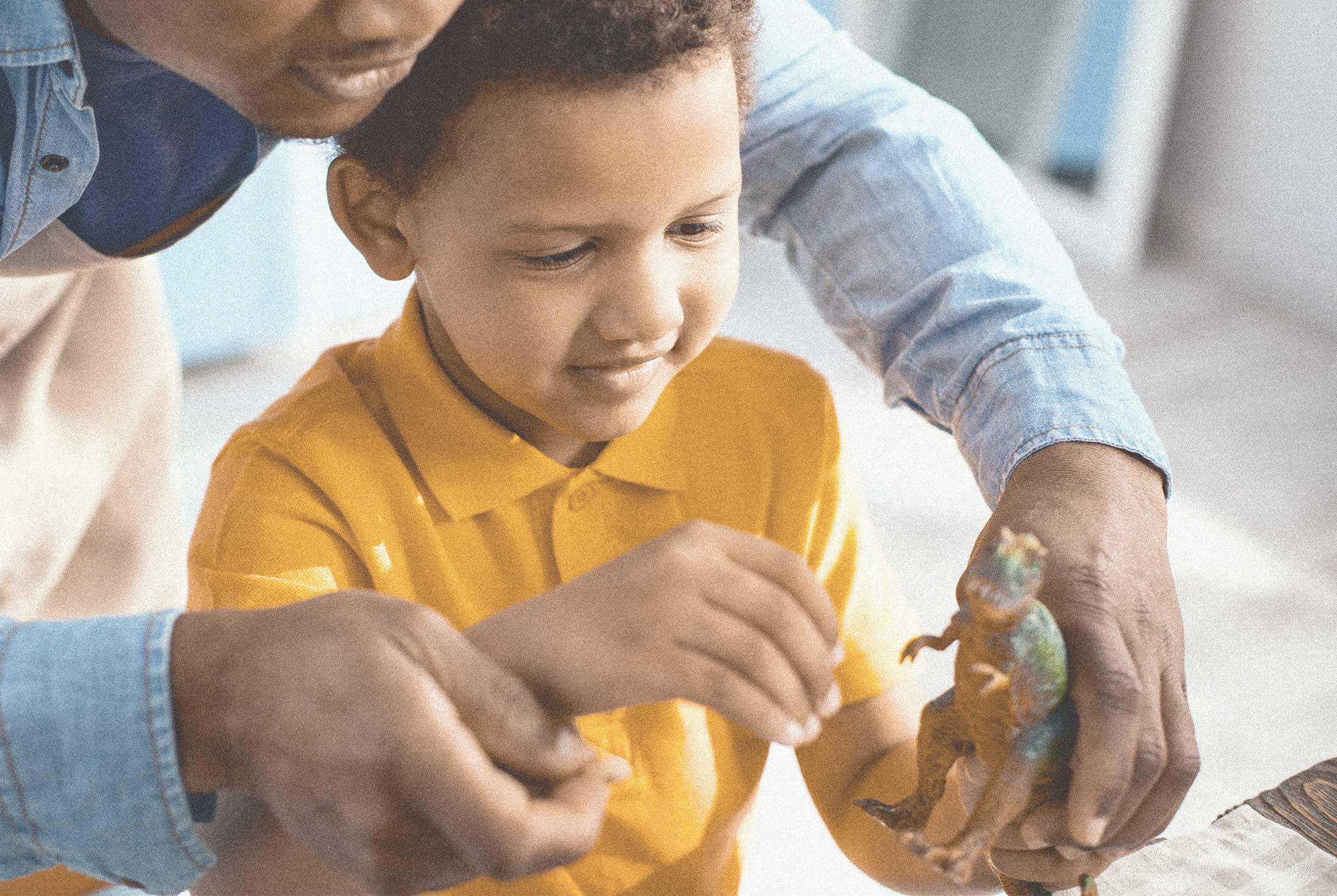 Man and child playing with a plastic dinosaur