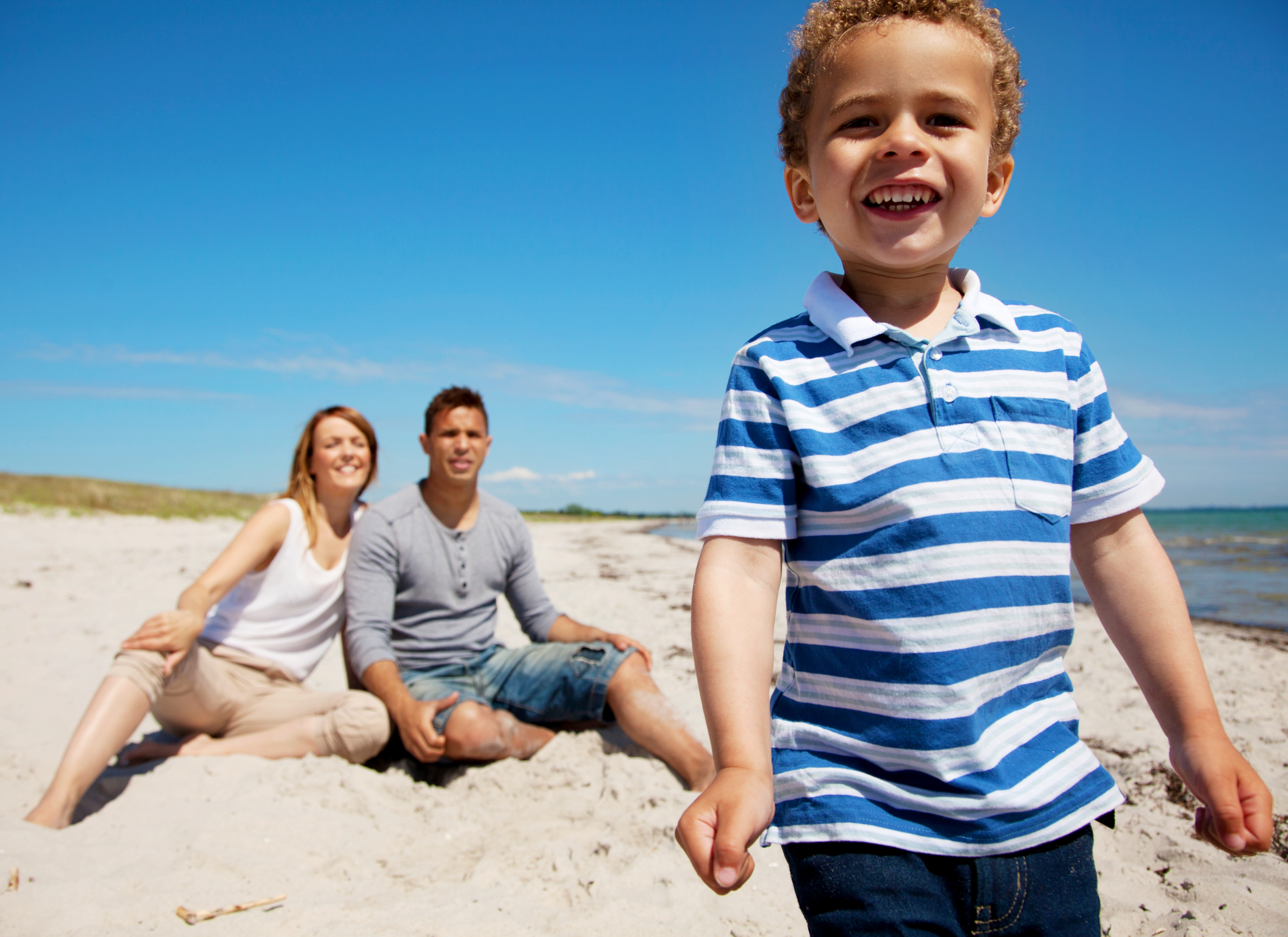 Charming kid with mom and dad on a beach