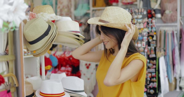 woman trying on hats in a boutique