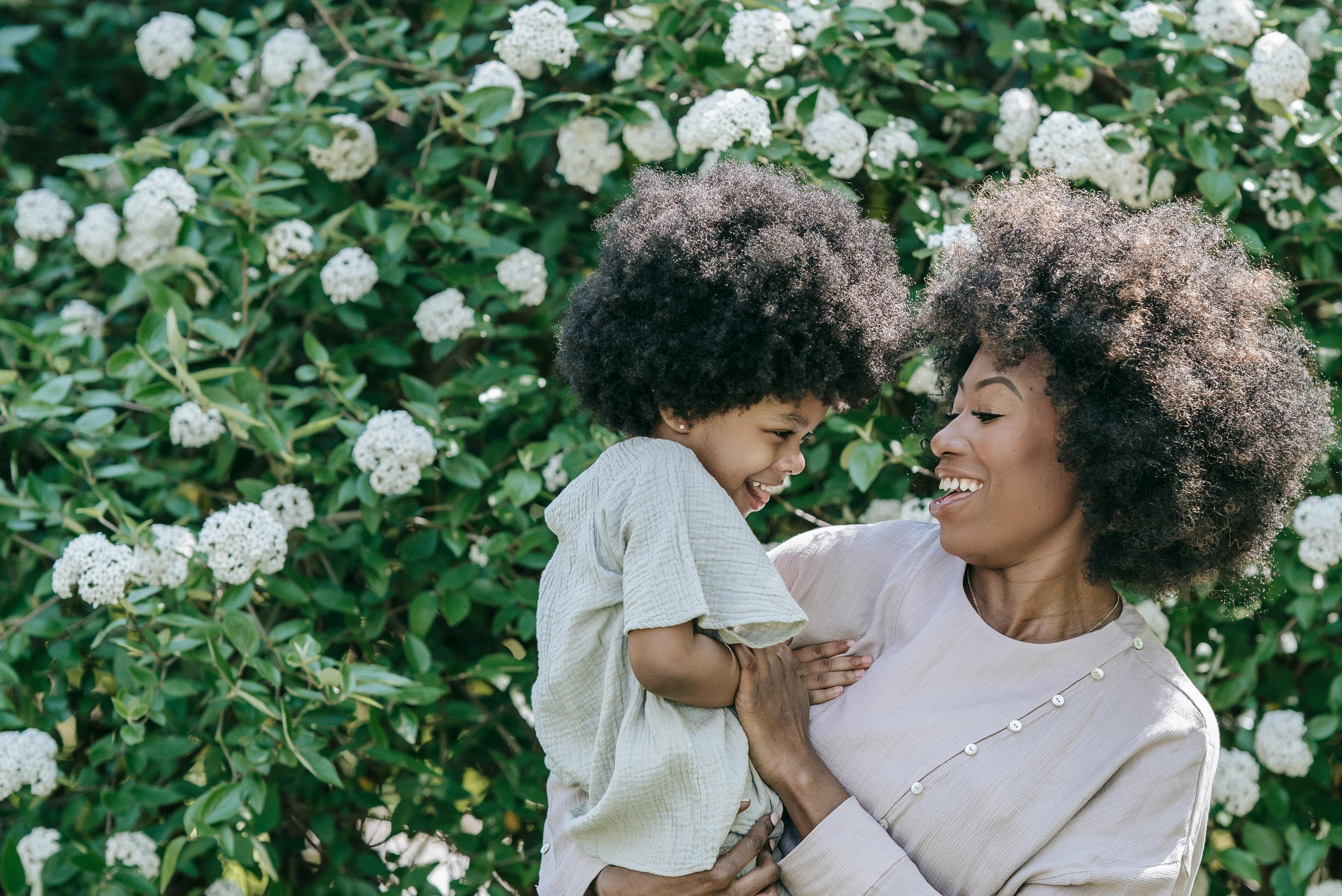 mother and child in front of blooming bush