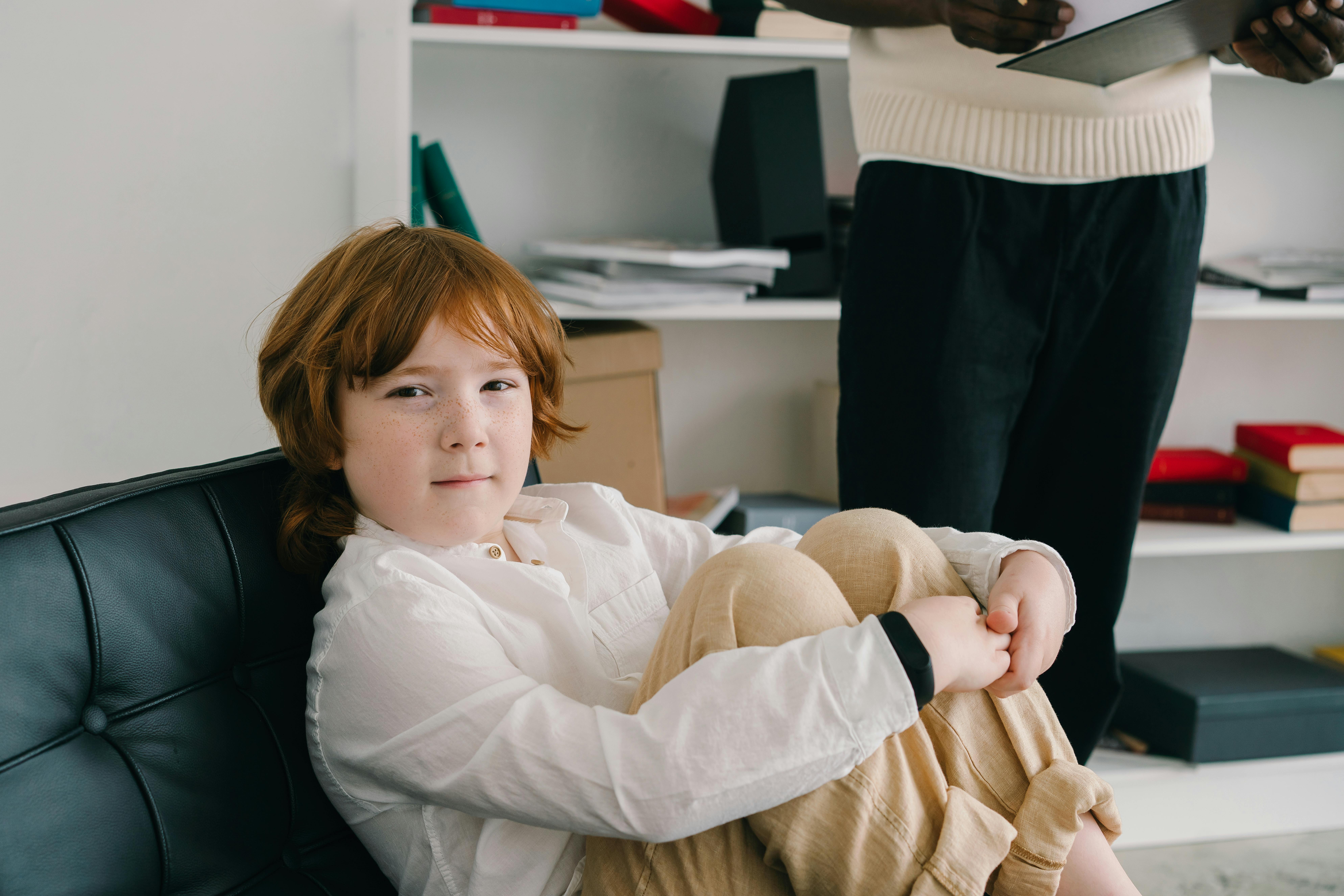 child on a couch with therapist in the background