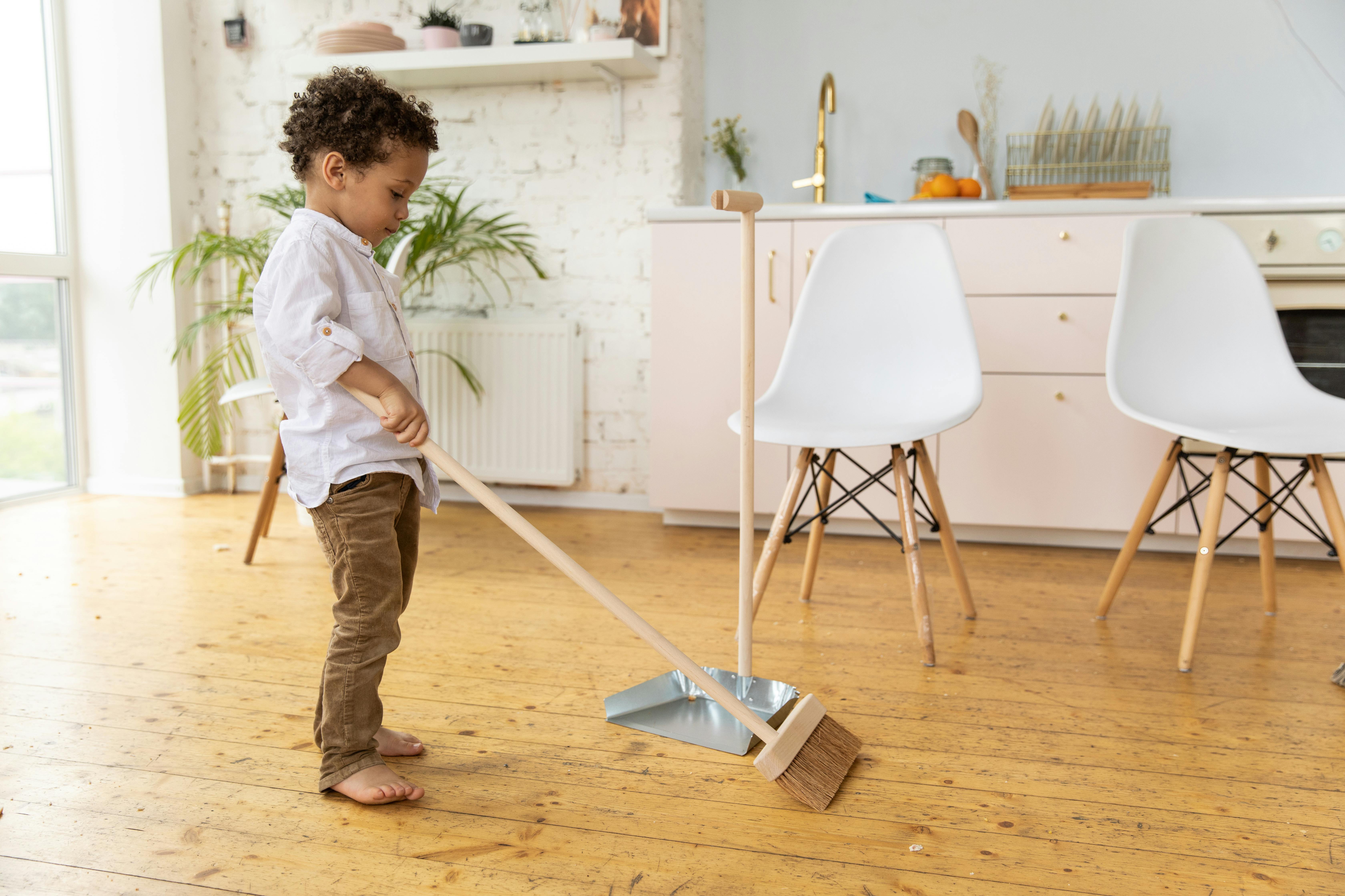 young boy sweeping the floor