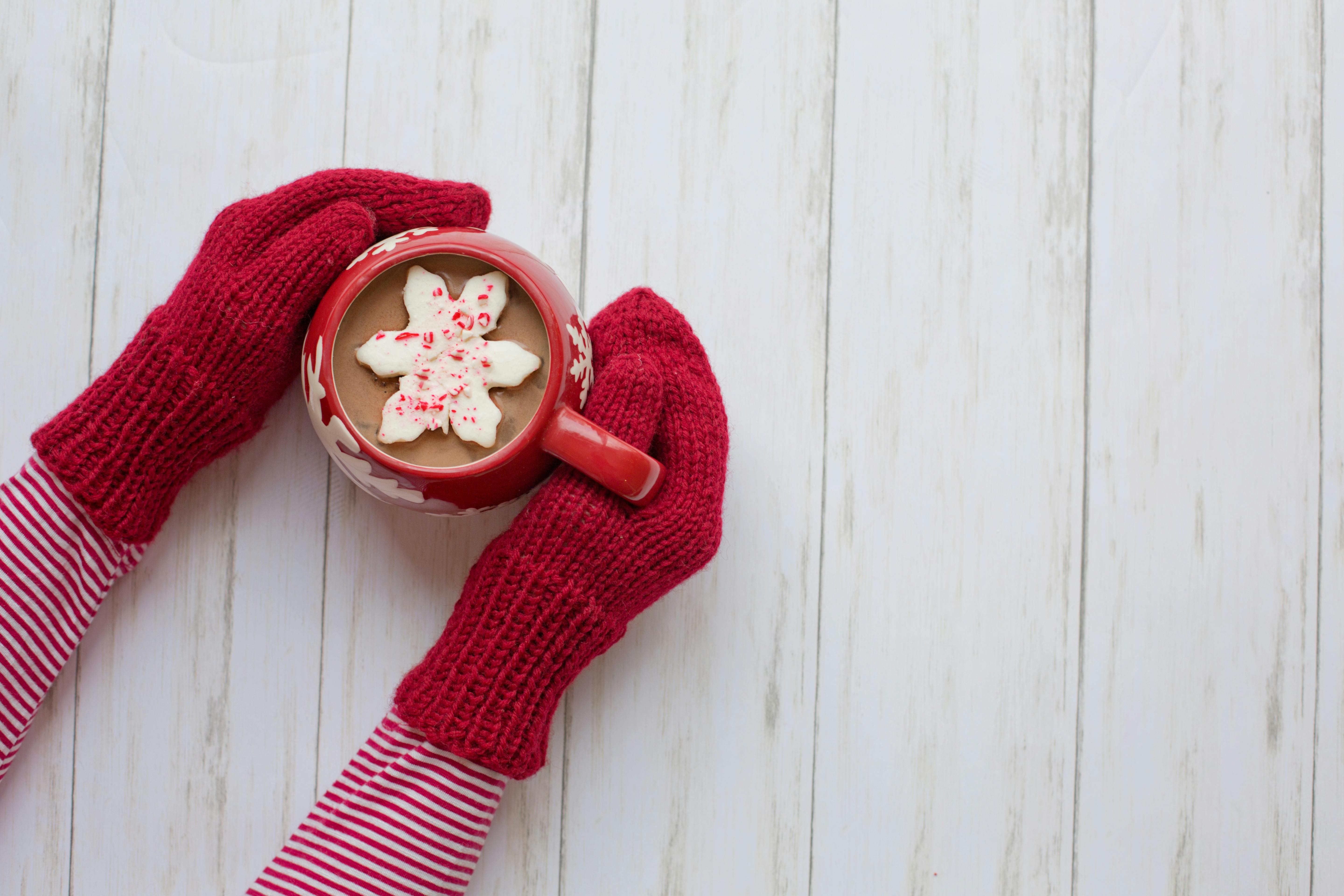 gloved hands holding hot chocolate