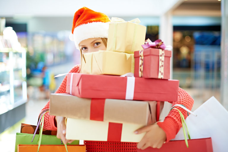 Woman in Santa hat with arms filled with gifts