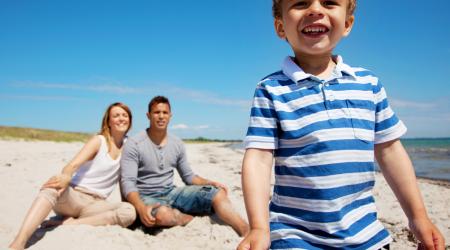 Charming kid with mom and dad on a beach