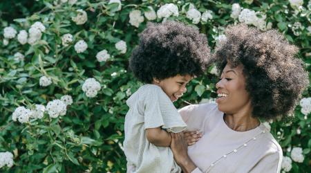 mother and child in front of blooming bush
