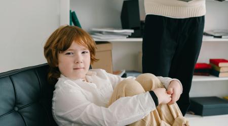 child on a couch with therapist in the background