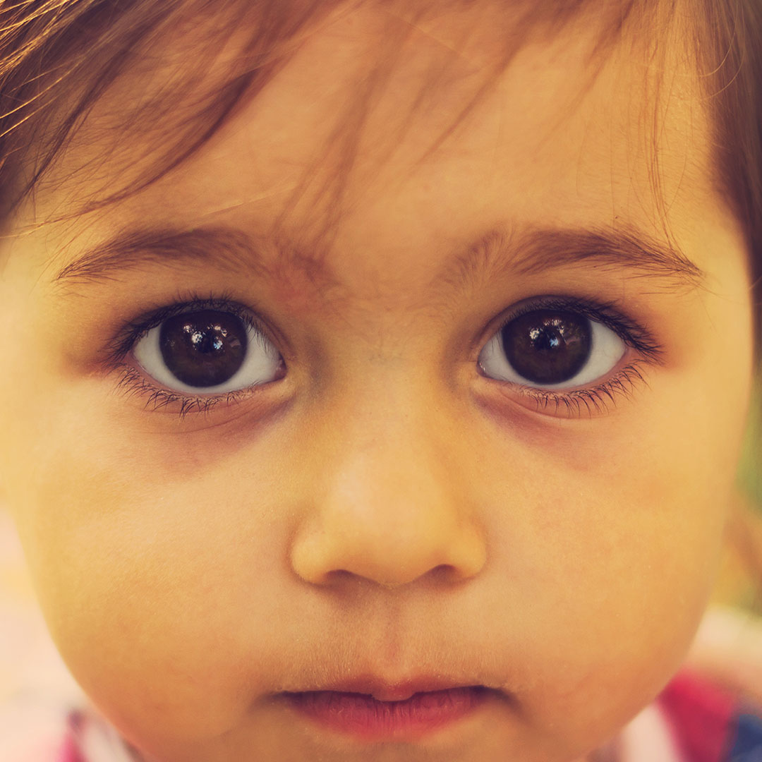 Young child with sad eyes looking at the camera.