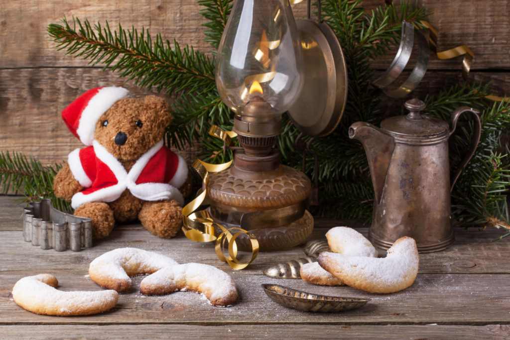 Christmas decoration with antique teddy bear in santa`s hat with burning vintage lamp and sugar cookies over wooden background